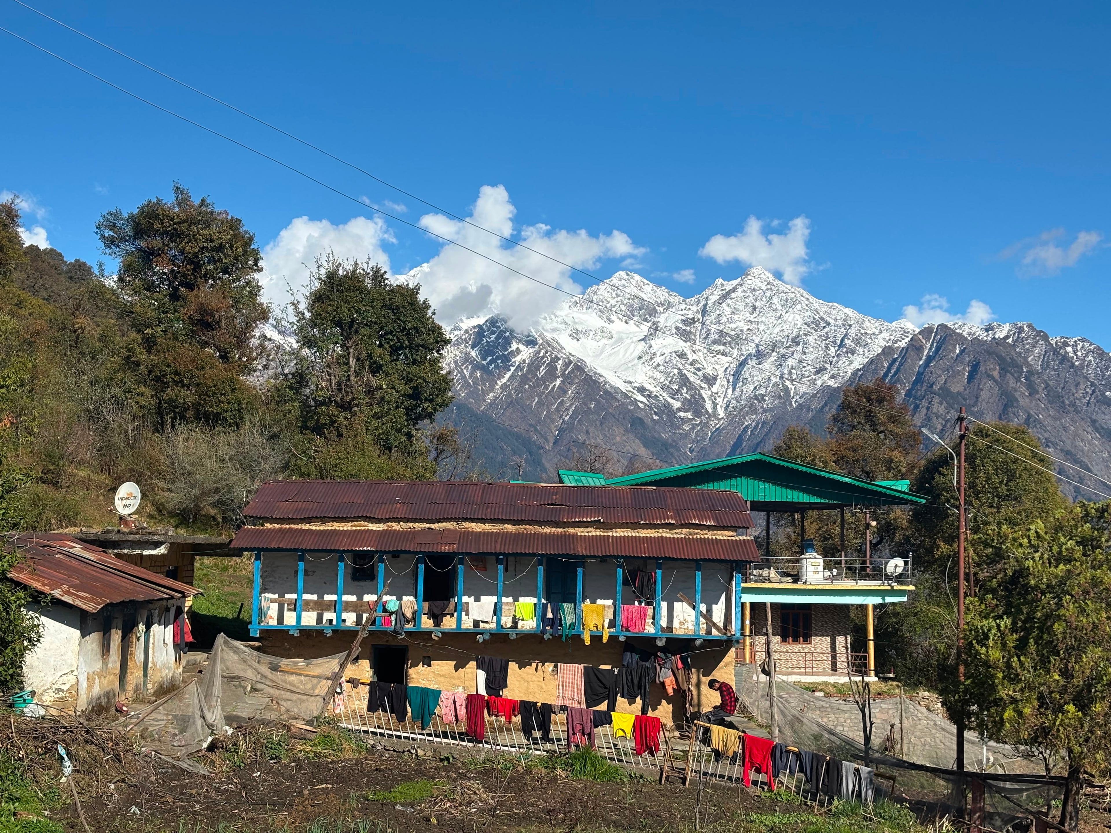 Pahadi village home below snow-capped Himalayan peaks in Uttarakhand