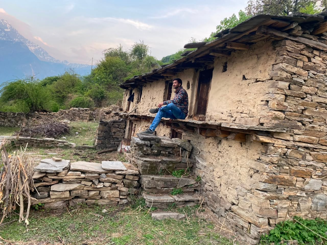 Traveller resting on the porch of an old stone house in a Himalayan village