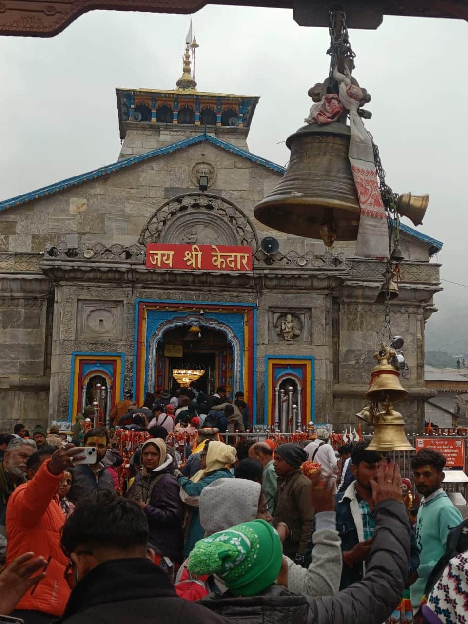 Pilgrims at Kedarnath Temple with the Jai Shri Kedar board and temple bell