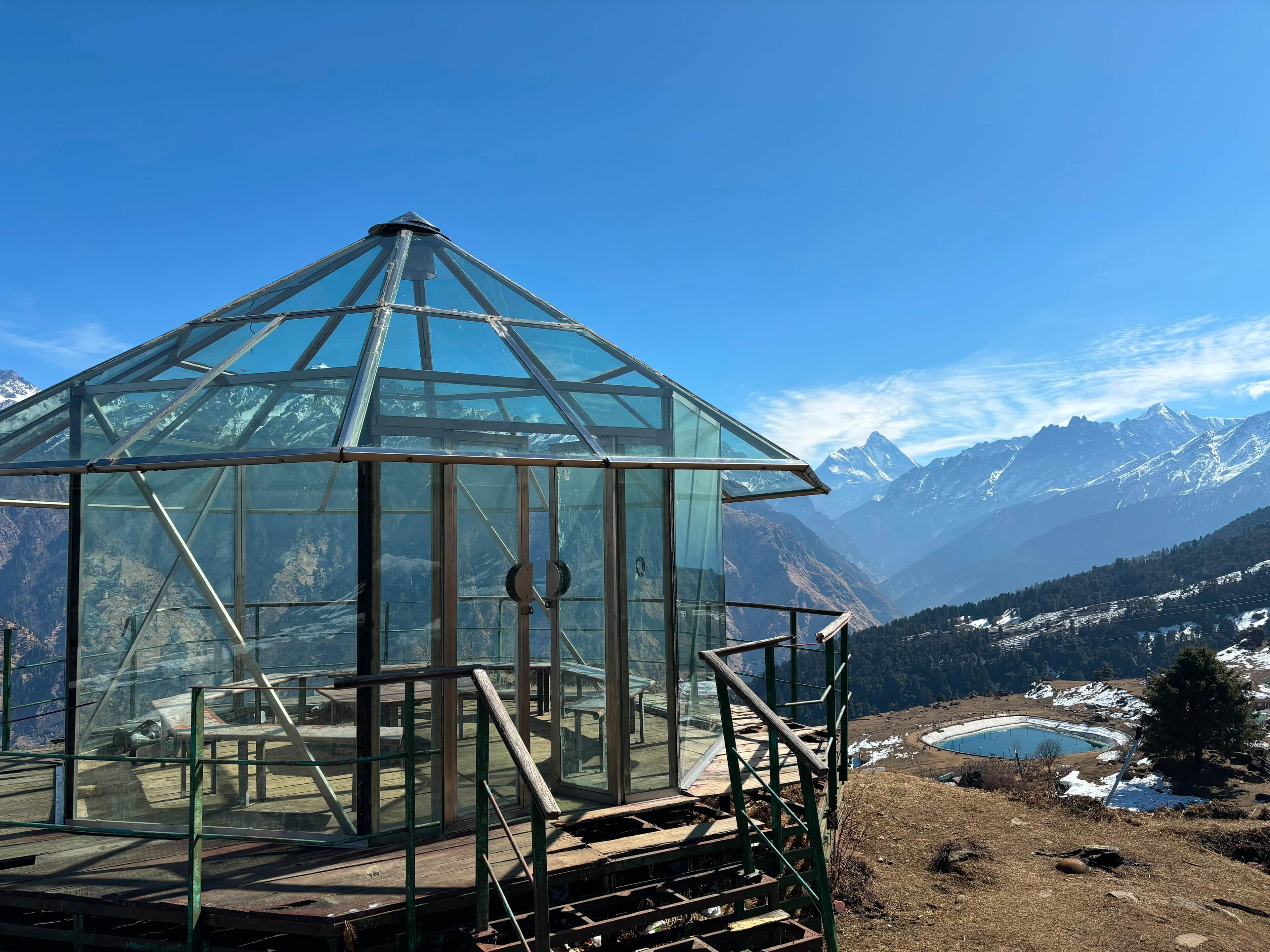 Glass viewpoint hut at Auli with the Auli lake and snow-capped Himalayan peaks
